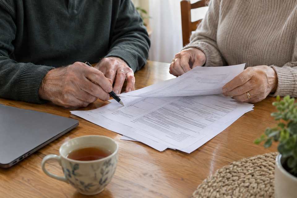 Two pairs of hands going over mortgage paperwork at a dining table