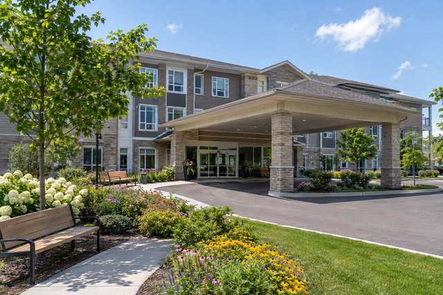 The front entrance of a retirement residence framed by flower gardens